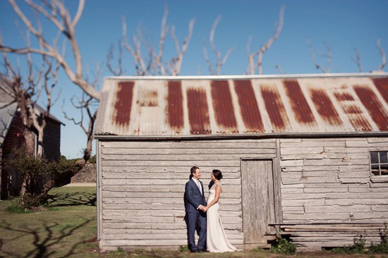 bride and groom against barn