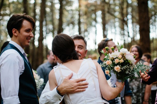 Bride being hugged at forest wedding