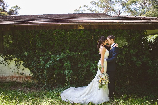 Bride and groom in front of ivy covered wall