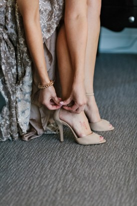 Bride doing up taupe shoes