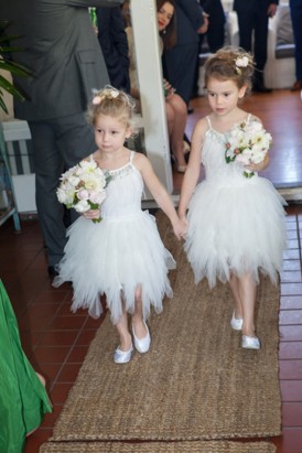 Flowergirls holding hands as they walk down the aisle