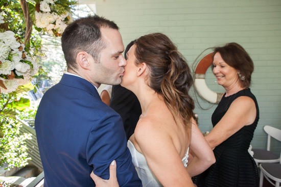 Groom kissing bride on cheek at ceremony