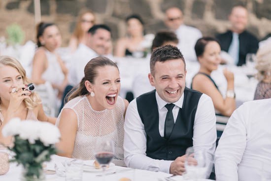 Newlyweds laughing at wedding speeches