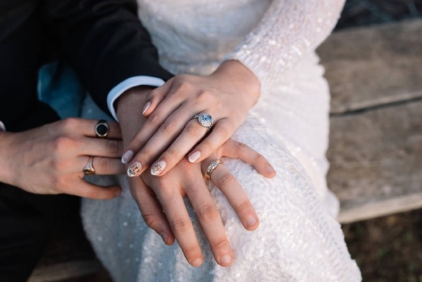 a bride and groom hands on laps with rings